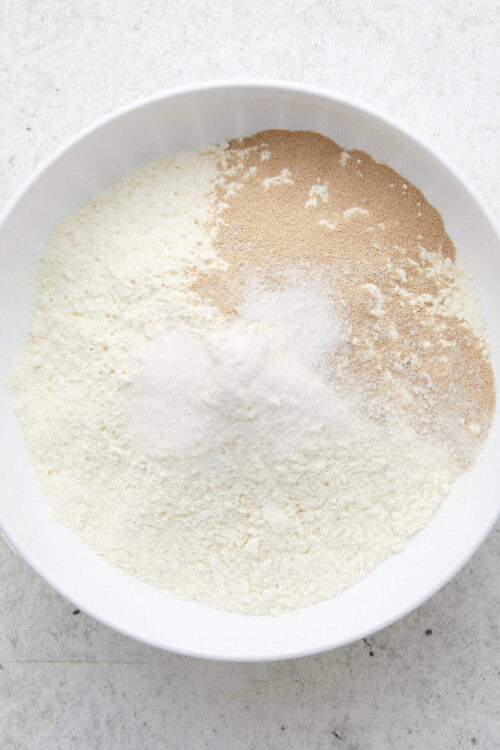 Flour, sugar, and baking ingredients in a white mixing bowl for baking recipes.