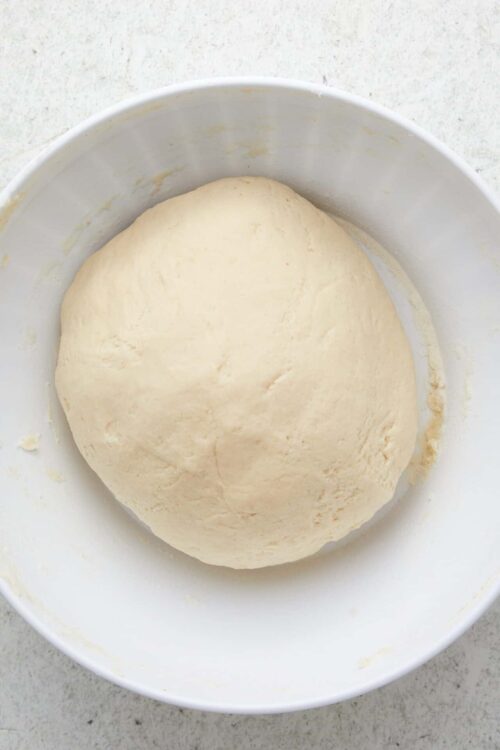 Soft, smooth bread dough in a white mixing bowl for baking recipes.