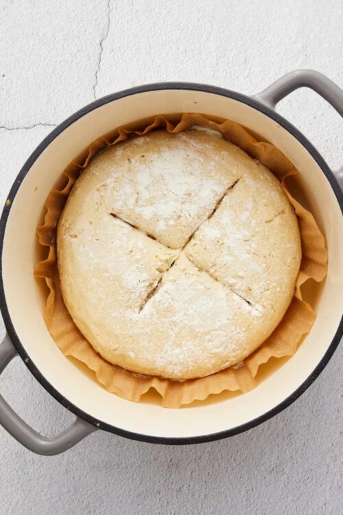 Fluffy baked bread dough in a black and white round cast iron skillet.