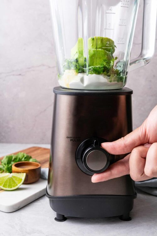 High-performance blender with fresh greens and ingredients inside.