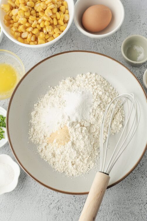 Flour, eggs, and corn ingredients for baking cornbread batter.