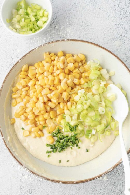 Buttered corn and chopped green onions in a mixing bowl.