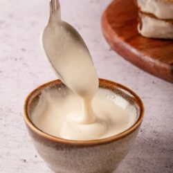 Creamy homemade sauce being scooped into a small bowl, perfect for baked dishes or dipping.