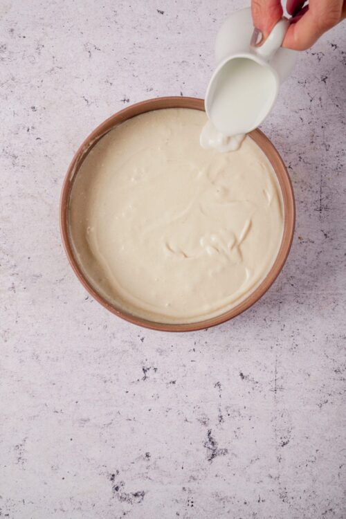Cream being poured into a bowl of cake batter for baking recipes.