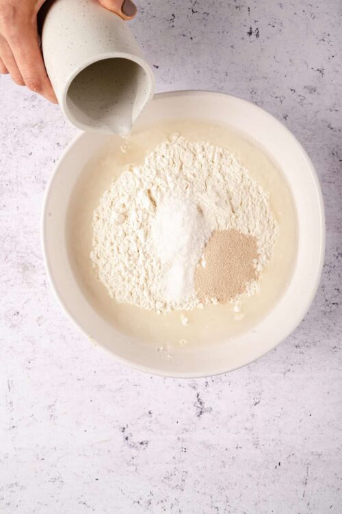 Flour mixture with milk being poured into a mixing bowl for baking recipes.