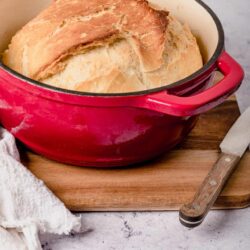 Golden baked bread in a red enameled Dutch oven.