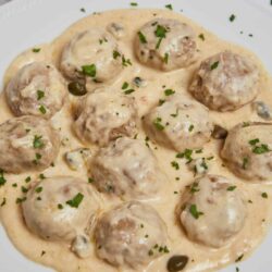Creamy chicken meatballs in a rich white sauce with capers and herbs.