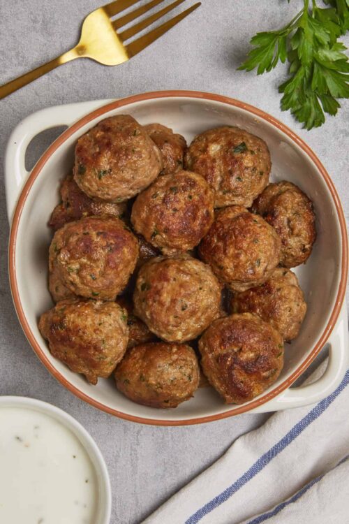 Savory homemade meatballs in a white dish, served with creamy dipping sauce. Perfect cozy comfort food.