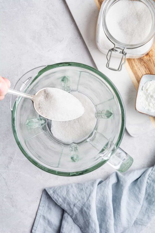 Powdered sugar being added to a glass mixing bowl for baking recipes.