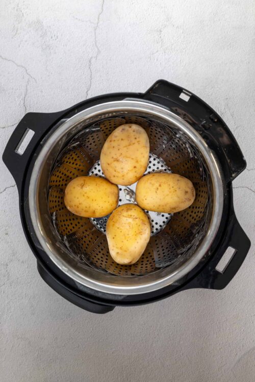Fresh potatoes inside an air fryer for healthy baked recipes.