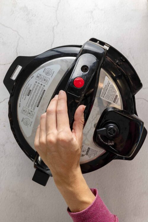 Cuisinart pressure cooker on white wall background.