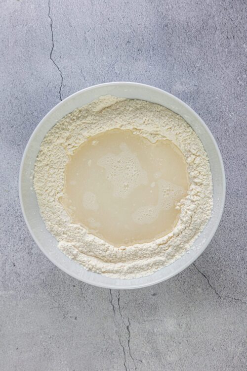 Flour and wet ingredients in mixing bowl for baking bread or pastry.
