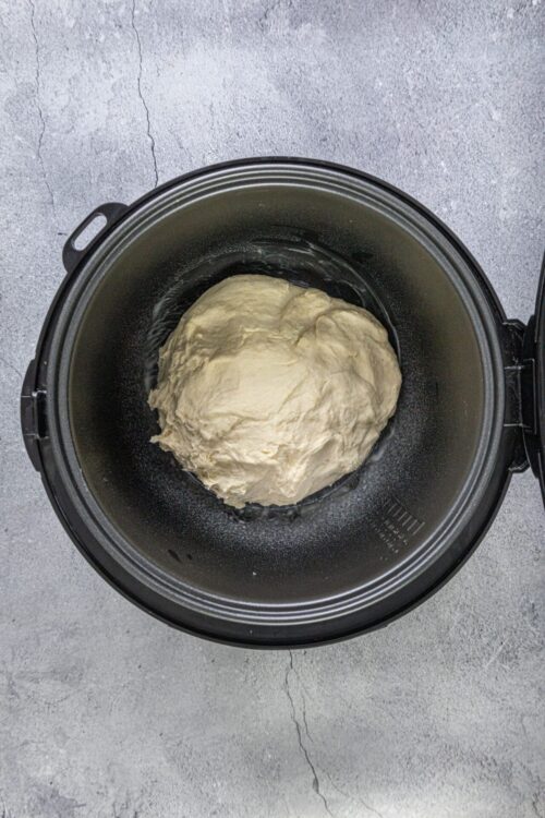 Dough in a bread machine ready to be baked, homemade bread preparation, bread dough in bread maker, baking bread on countertop.