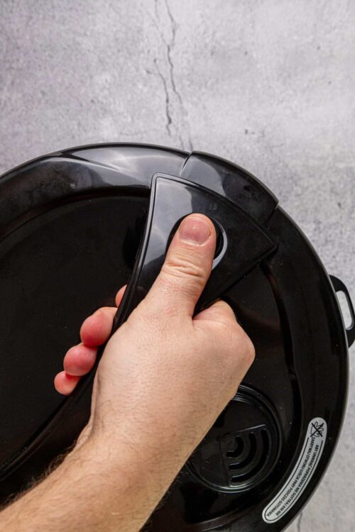 Oil spray machine being used on a non-stick cooking appliance, close-up image.