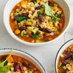 Roasted vegetable minestrone soup in white bowls, healthy plant-based vegetarian meal.