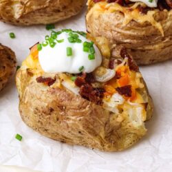 Crispy baked potato skins stuffed with cheese bacon and sour cream, garnished with chives.