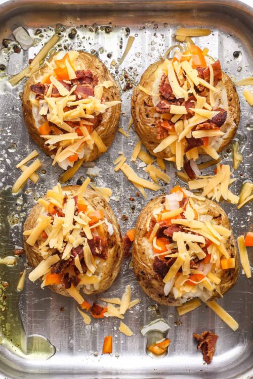 Baked stuffed potatoes topped with cheese, bacon, and vegetables, ready for serving.