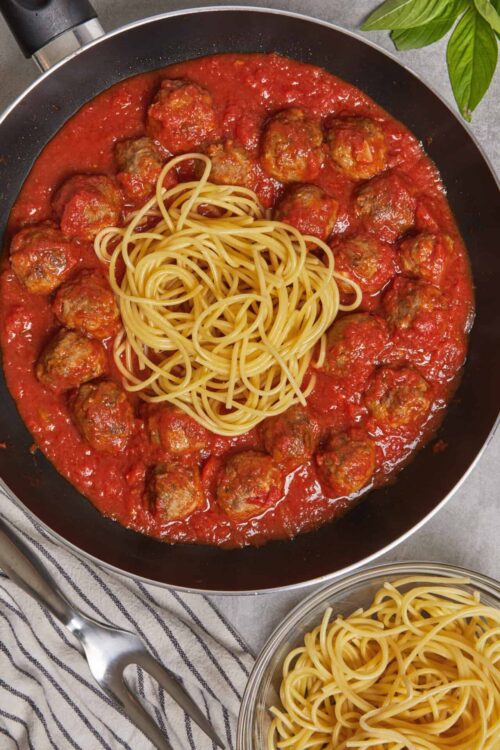 Savory meatballs in marinara sauce with spaghetti, served in a black skillet.