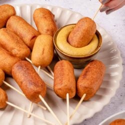 Crispy croquettes with dipping sauce served on a white plate.
