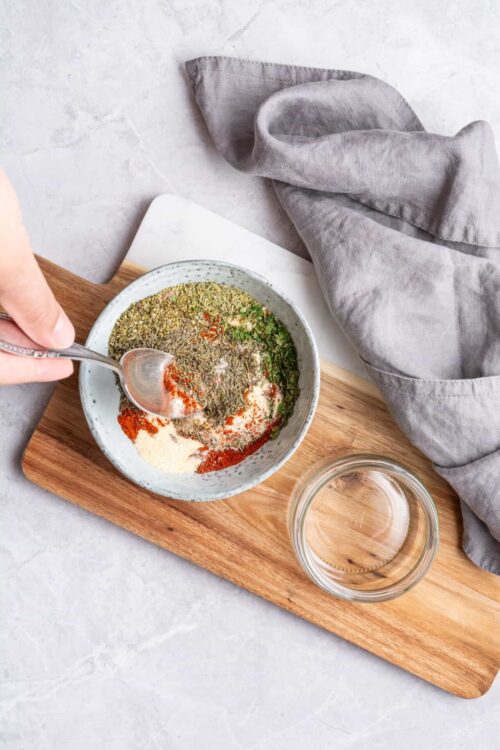 Dried herbs and spices in a bowl on a cutting board for baking and cooking.