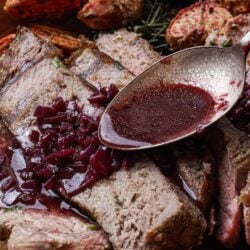 Slow-cooked beef brisket with cherry port wine sauce and roasted vegetables, served for a hearty meal.