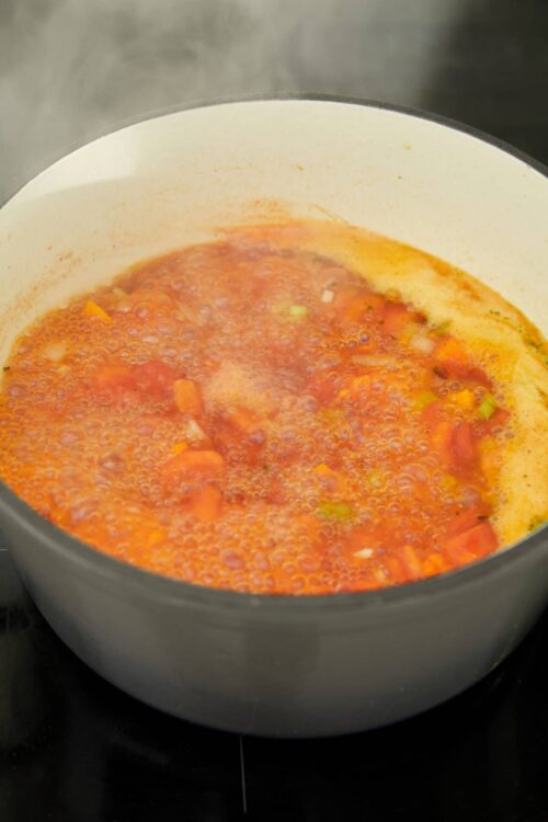 Sweet vegetable soup simmering in a white pot on the stove.