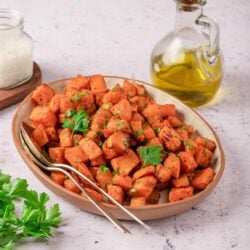 Sweet potato hash with fresh herbs and olive oil in a rustic ceramic dish.