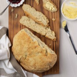Fresh homemade bread with butter and jam on a wooden cutting board.