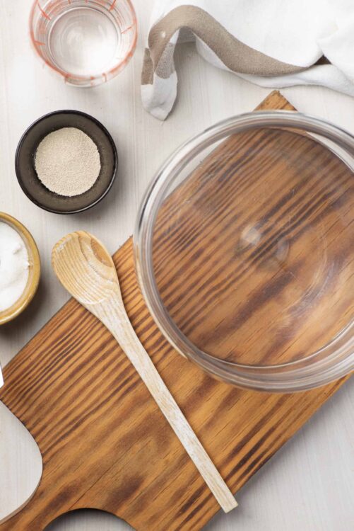 Flour, water, and baking ingredients on a wooden cutting board for baking bread or pastry.