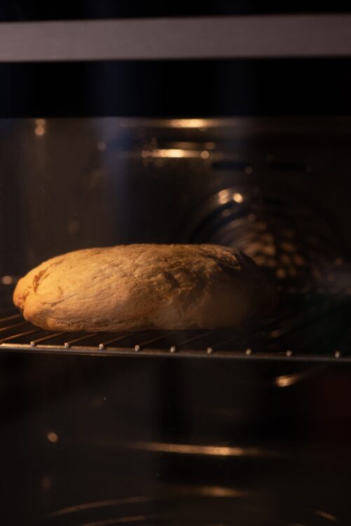 Baked bread loaf in an oven, warm baking process for fresh homemade bread.