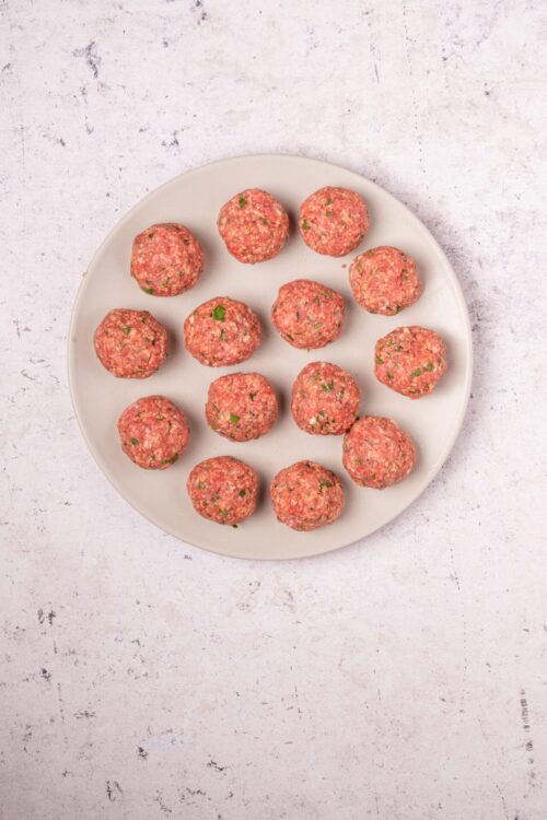 Raw meatballs on a white plate for healthy meal prep.