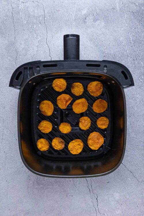 Crispy air fryer chicken nuggets on a black tray.