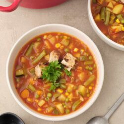 Creamy vegetable minestrone soup with fresh herbs in a white bowl.