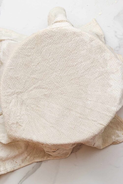 Cream textured woven blanket on marble surface, cozy home decor element.