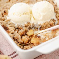 Butterscotch apple crumble with vanilla ice cream in a baking dish.