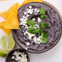 Creamy black bean dip garnished with fresh cilantro, served with tortilla chips and lime wedges.