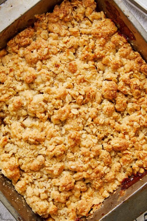 Golden apple crumble topping with oats in a baking dish.