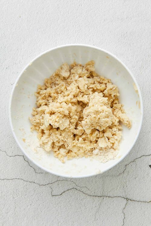 Buttery pie crust dough for baking, close-up in a white bowl.