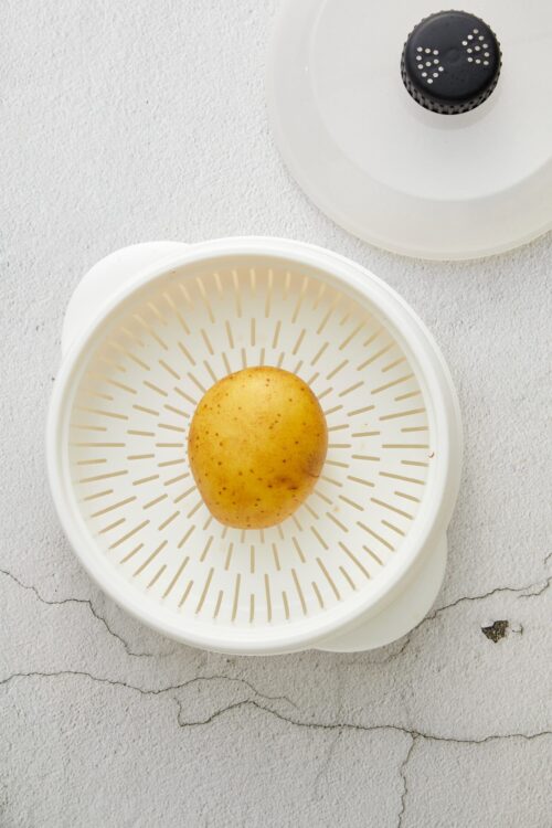 Fresh yellow potato on a white food mill for healthy cooking and recipes.