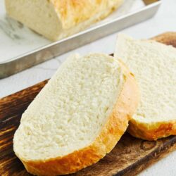 Fresh homemade white bread on wooden cutting board, sliced and ready to serve. Perfect for sandwiches or toast.