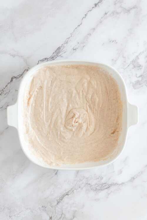Creamy cinnamon-spiced ice cream base in a white baking dish on marble surface.