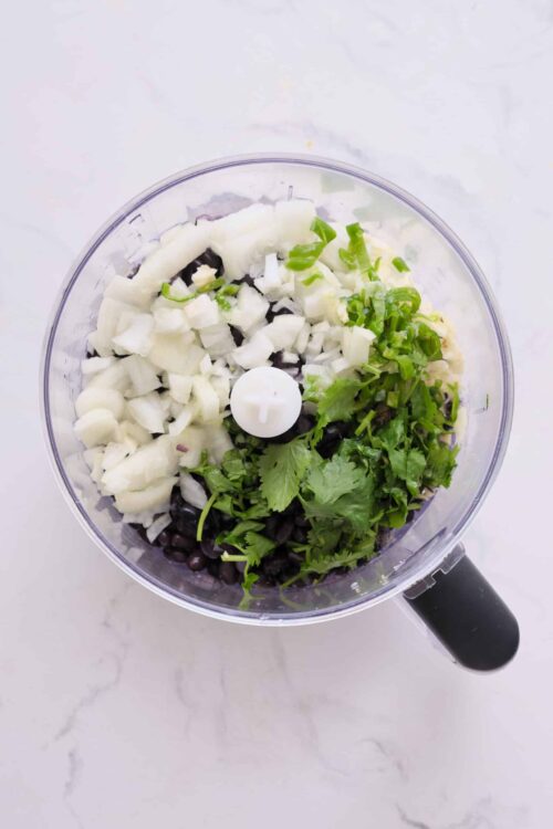 Chopped onions, black beans, cilantro and jalapeños in food processor for a healthy recipe.