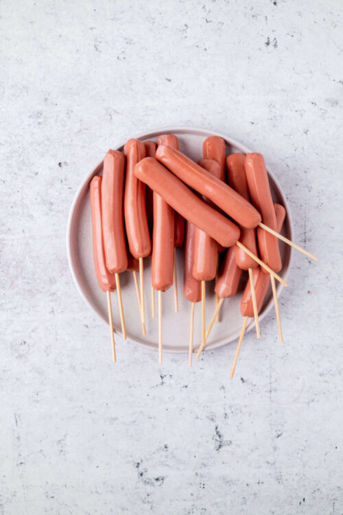 Mini hot dogs on skewers, ready for party appetizers or snacks. Perfect for casual gatherings and game day celebrations.