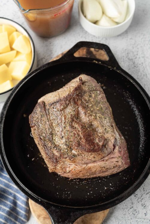 Juicy roasted beef tenderloin cooking in a cast iron skillet, surrounded by ingredients for a delicious meal.