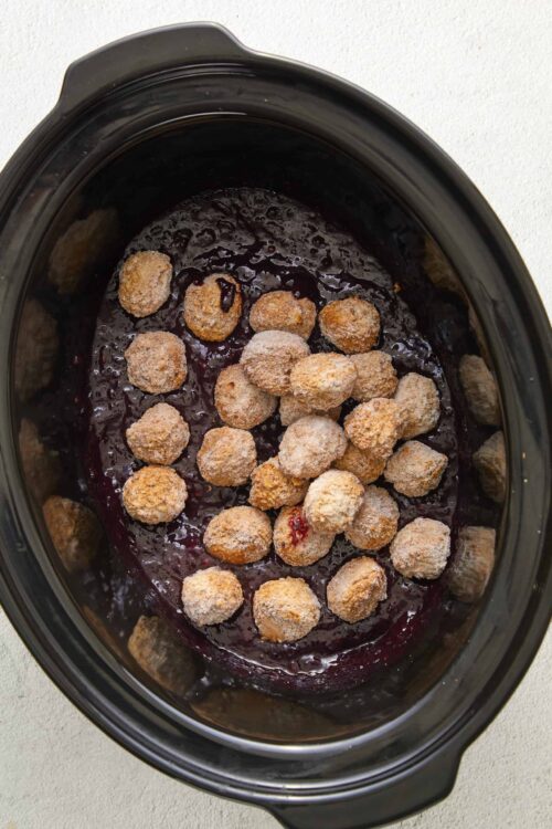 Creamy berry cobbler filling with bread crumb topping in slow cooker.
