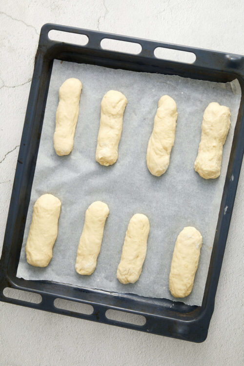Unbaked bread dough shaped into baguettes on a baking sheet.