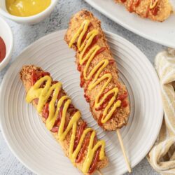 Crispy chicken tenders on sticks with ketchup and mustard drizzle. Perfect appetizer or snack, easy homemade chicken tender recipe.