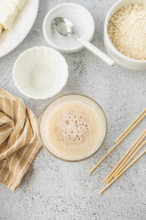Creamy smoothie with milk, surrounded by baking ingredients and utensils on a textured countertop.