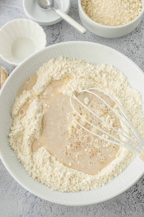 Flour and wet ingredients mixing in a large bowl for baking bread or pastries.