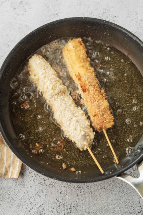 Crispy fish sticks frying in oil in a black skillet, homemade seafood recipe, baked bree cuisine.
